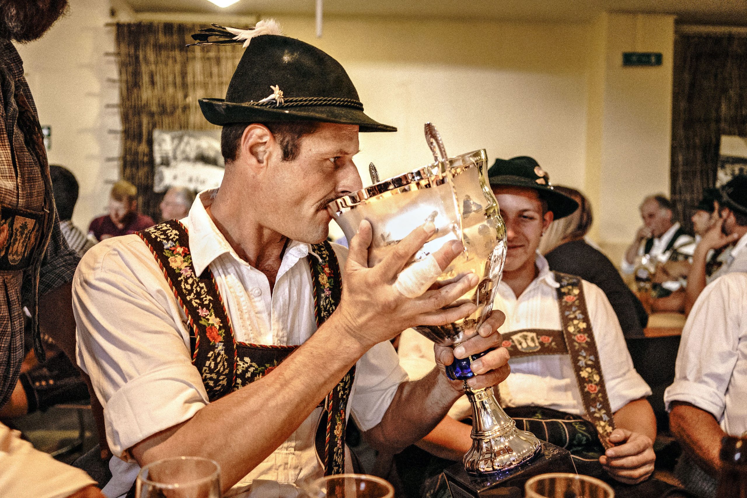 Ein Fingerhakler in Tracht trinkt aus einem Pokal.