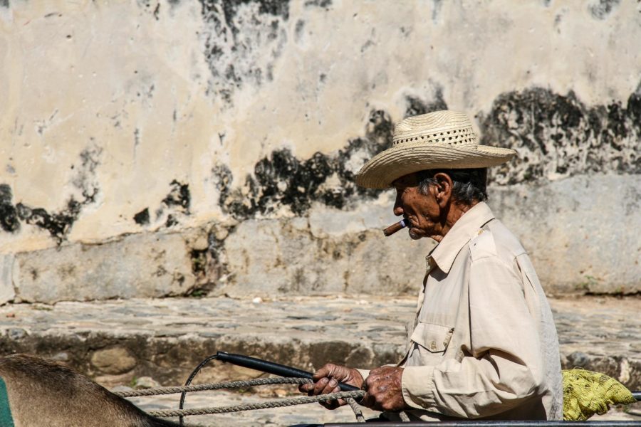 Ein alter zigarrenrauchender Mann reitet durch Trinidad.